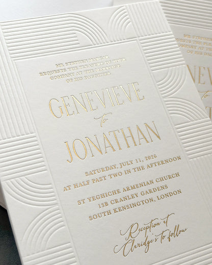 Art Deco invitation angled close-up showcasing embossed wave-pattern detail and gold foil couple's names with event information, layered composition with second card partially visible — Polina Perri