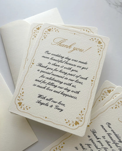 Stack of custom thank you cards with a gold heart frame and script message on textured cream paper