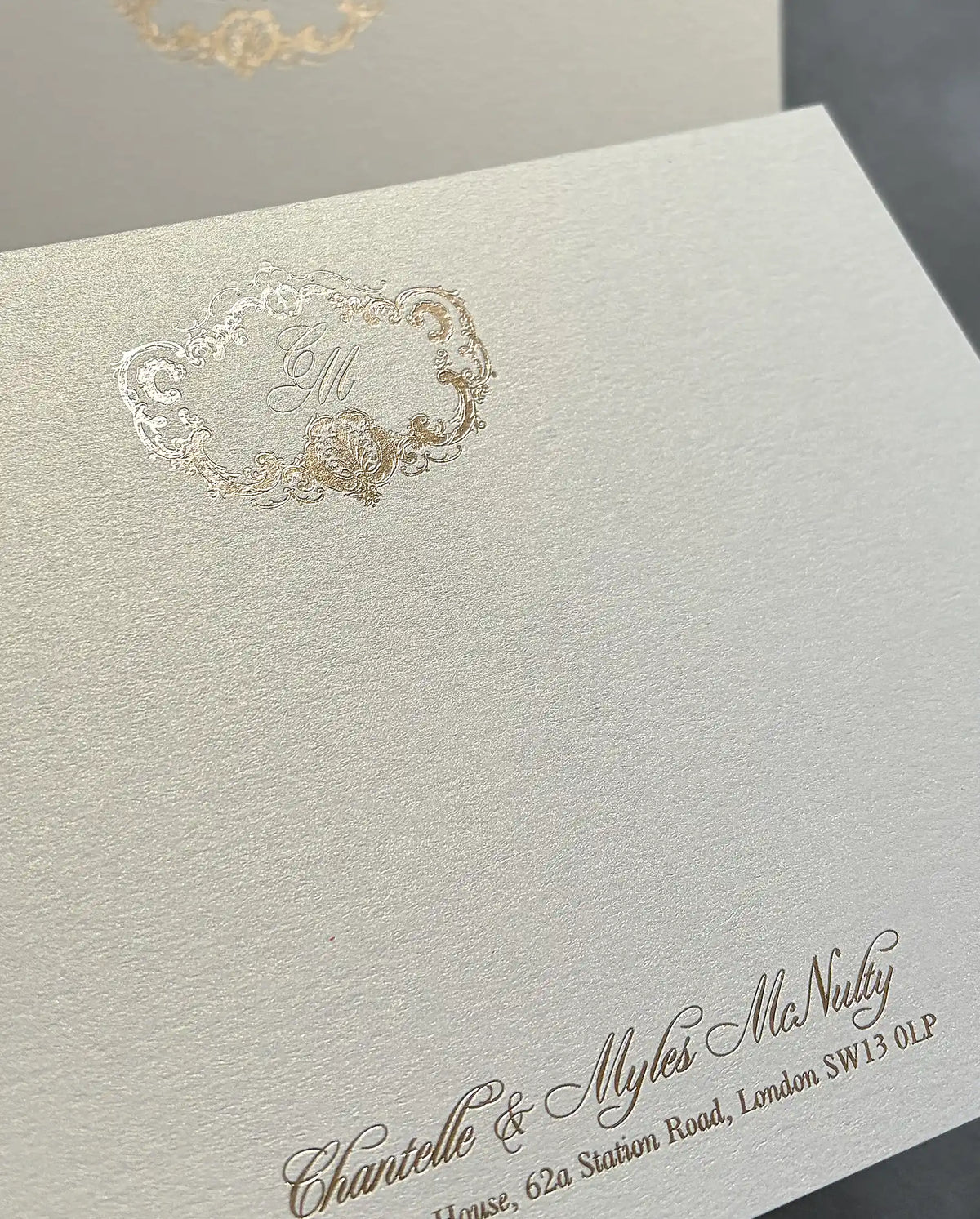 Close-up of shimmer cardstock thank-you card with gold foil crest monogram and foil-pressed names on the lower edge