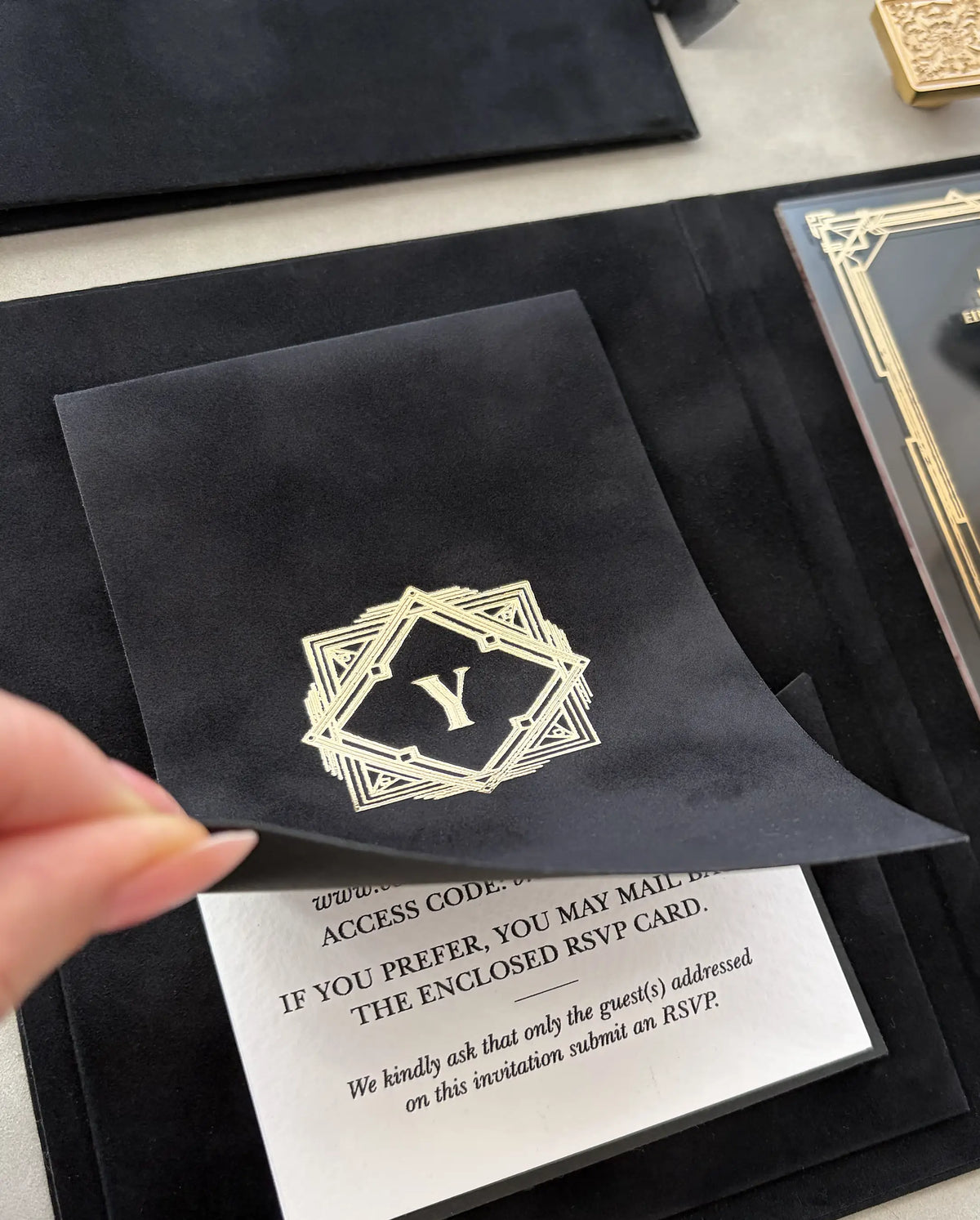 Great Gatsby Folio Invitation velvet mini-book opened to reveal RSVP details card, with gold foil Art Deco monogram on black velvet cover — Polina Perri